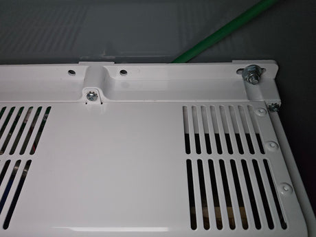RV rental: Close-up of a white perforated vent panel, revealing interior wiring and a green cable connection.