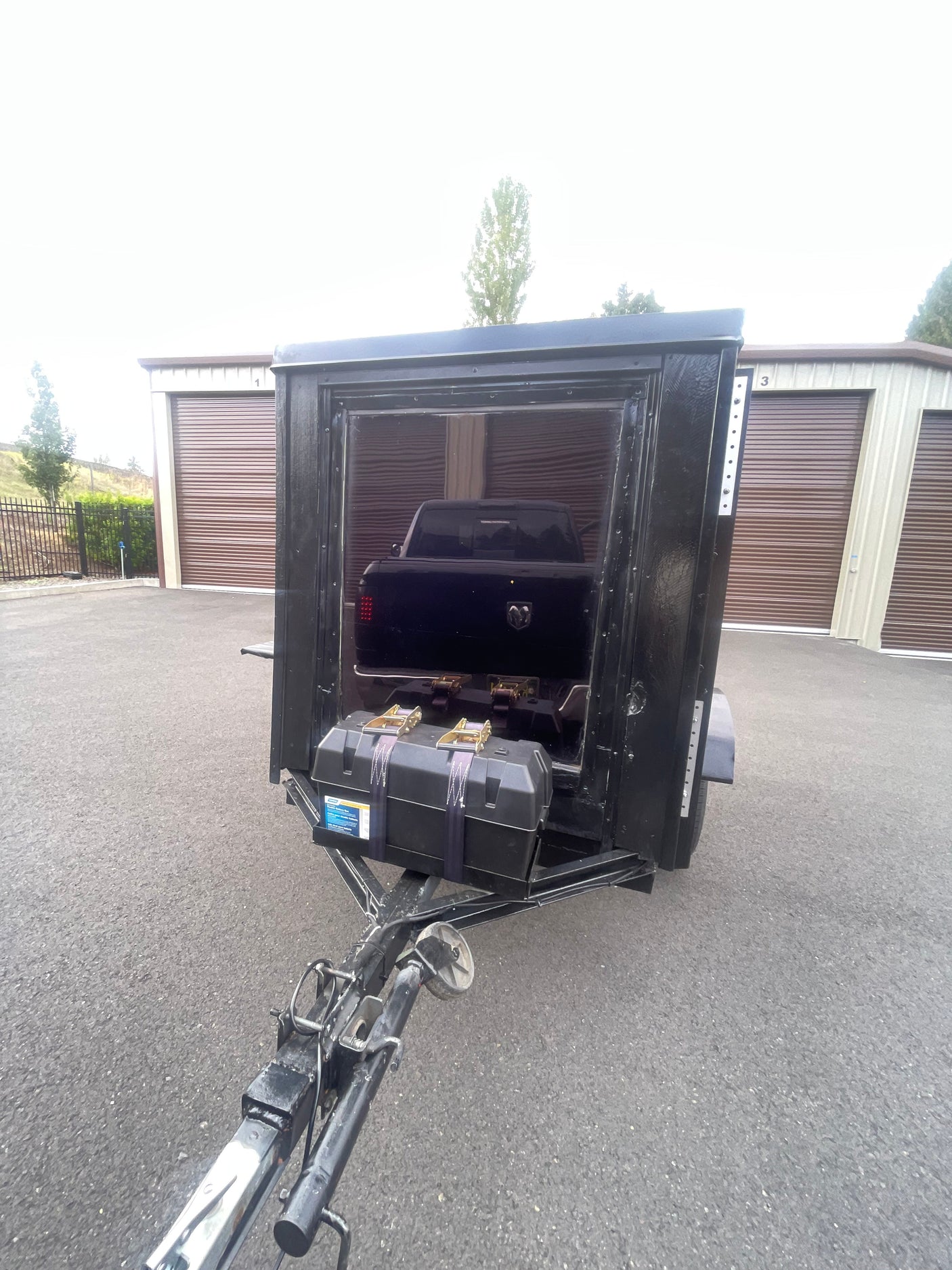 Black cargo trailer with truck and battery box at storage units. Perfect for hauling extra gear for your rv rental trip.