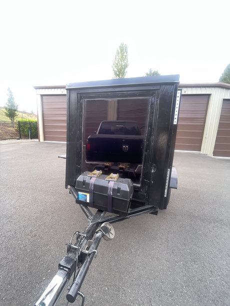 Black cargo trailer with truck and battery box at storage units. Perfect for hauling extra gear for your rv rental trip.