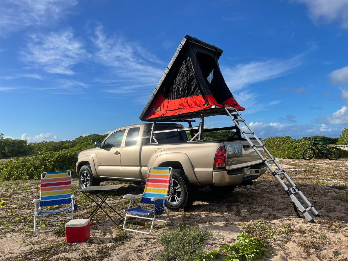 Your next RV rental adventure awaits! Tan Tacoma with rooftop tent, chairs, & cooler set up for camping. — photo 6