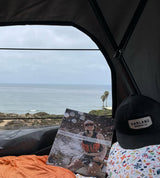 Relaxing in an RV rental overlooking the ocean. Reading an Adventure Journal with a Harland Brewing cap.