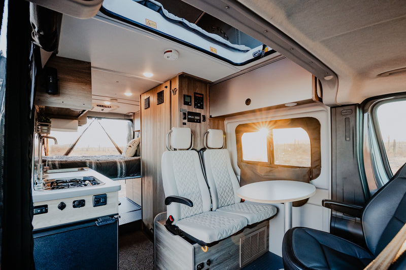 Step inside this modern RV rental: a spacious camper van interior with kitchenette, comfortable seating, and a cozy bed in back. — photo 2