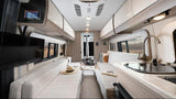 Modern RV rental interior: comfortable seating, central dining table, compact kitchen, and TV.