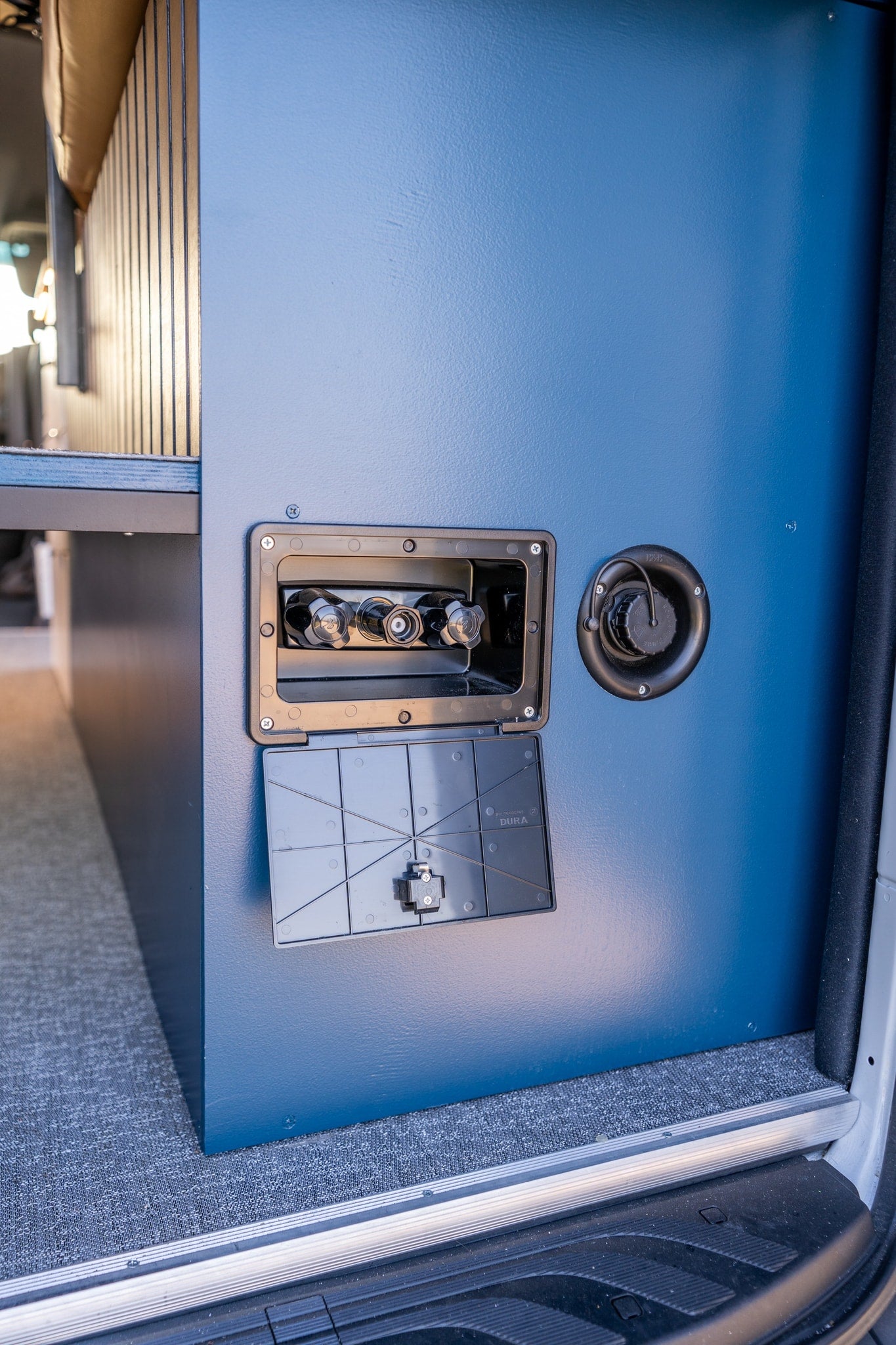 RV rental's internal blue cabinet with open utility access, revealing water/gas quick-connect hookups. — photo 13