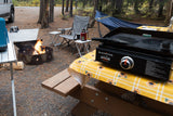 RV rental camping setup with a Blackstone griddle, campfire, and hammock for a relaxing outdoor experience.