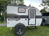 This Sunray Sport, a compact RV rental teardrop camper with rugged tires, is ready for outdoor adventure and camping.