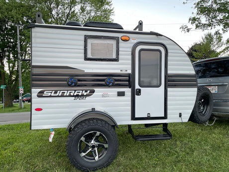 This Sunray Sport, a compact RV rental teardrop camper with rugged tires, is ready for outdoor adventure and camping.