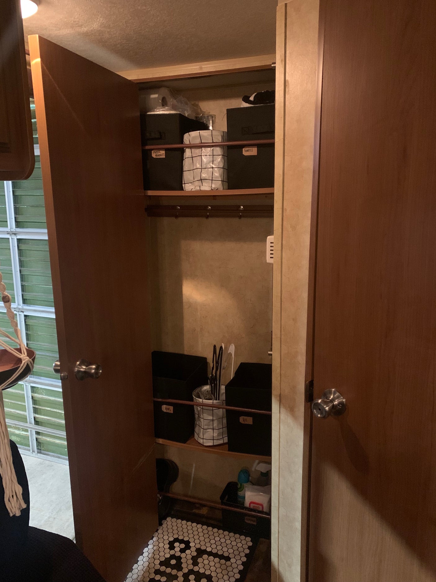 RV rental storage solutions: organized closet with labeled bins for 'Paper Products', 'Towels', 'Hers', 'His', and a tiled mat.