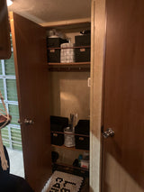 RV rental storage solutions: organized closet with labeled bins for 'Paper Products', 'Towels', 'Hers', 'His', and a tiled mat.