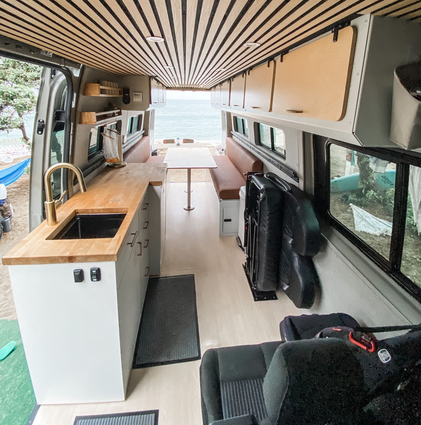  against Yosemite's majestic El Capitan. Epic van life!|An RV rental provides beach camping comfort. Family enjoys the ocean view with a blue hammock strung between trees and the van.|Stunning RV rental: interior of a modern camper van with kitchen — photo 2