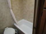 RV rental bathroom with white toilet, tub/shower, and a pulled-back light shower curtain. Practical onboard amenities.