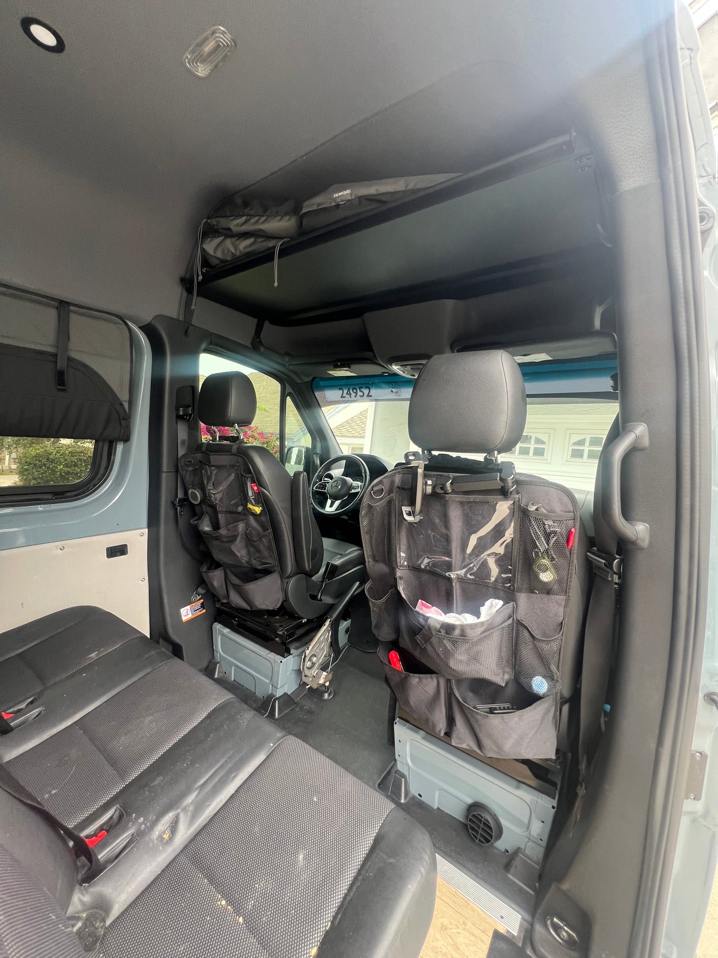 An RV rental's spacious interior from the rear. Front seats, rear bench, and overhead storage are visible.