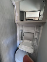 This RV rental's compact wet bath features a shower, mirror, and a space-saving sink installed over the toilet.