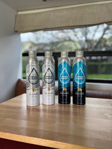 Four reusable Proud Source sparkling & spring water bottles on a table in an RV rental, ready for adventure.