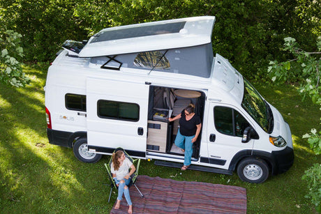 Discover adventure with this Winnebago Solis rv rental. Two women enjoy camping outside their pop-top camper van.