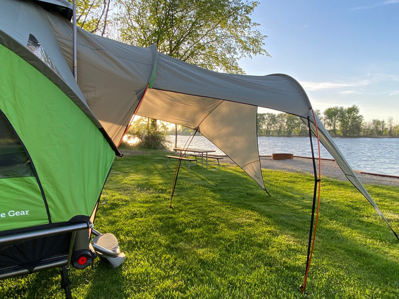 This inviting lakeside scene, perfect for an RV rental getaway, features a green tent and large grey awning by a picnic table. — photo 11