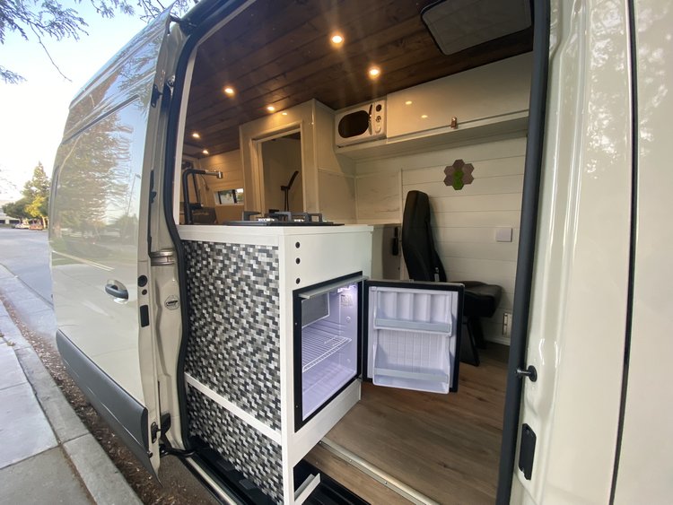  with a side ladder & open rear doors.|Spacious RV rental interior features a custom bed platform with under-bed storage — photo 18