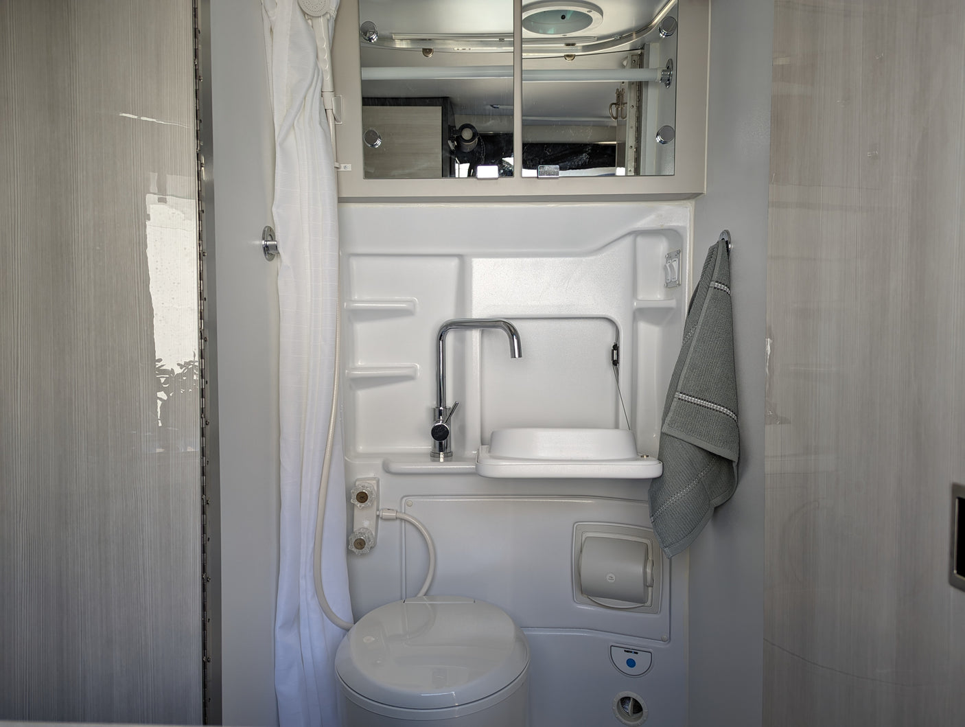 This RV rental wet bath features a space-saving toilet, fold-down sink, and shower, perfect for mobile travel comfort.