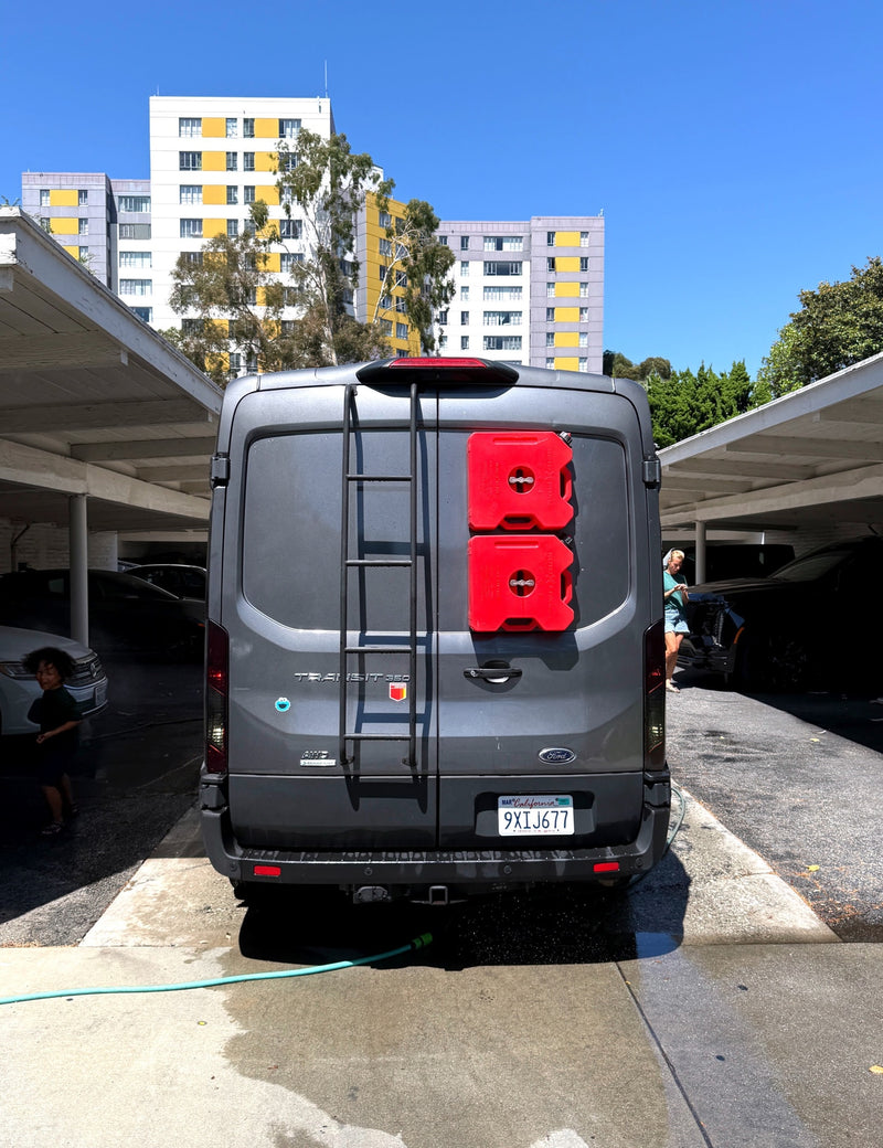 Washing a gray Ford Transit RV rental, equipped with a ladder and red Rotopax containers, on a sunny day. A child is nearby. — photo 3
