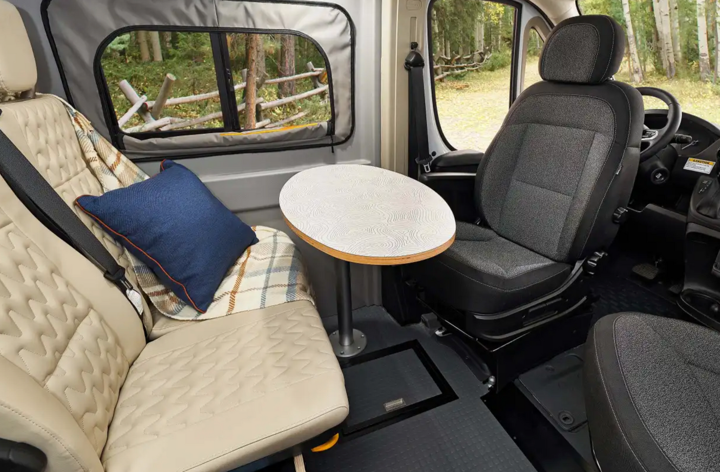 Step into comfort: This RV rental features a cozy bench seat, a swivel front seat, and a table, all with a forest view.