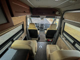 RV rental interior: View from rear, showing front cockpit, comfortable tan seats, overhead storage, and windows.