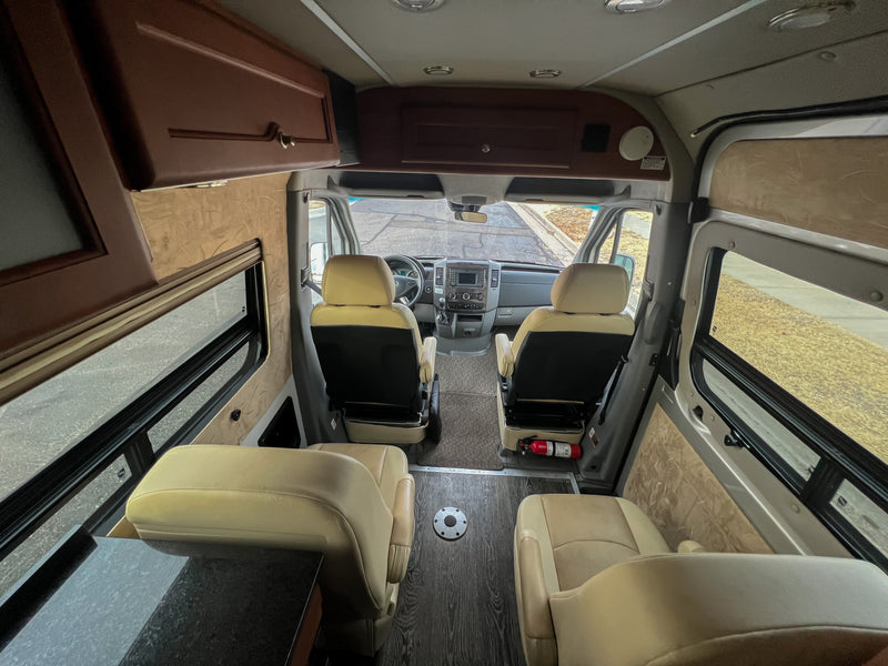 RV rental interior: View from rear, showing front cockpit, comfortable tan seats, overhead storage, and windows. — photo 7