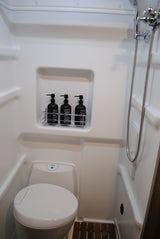 Step inside this compact RV rental bathroom, featuring a modern toilet, a refreshing shower, and organized amenities for your comfort.
