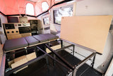 Inside this RV rental: a flexible interior with modular bed, table, & control station, ready for your next adventure.