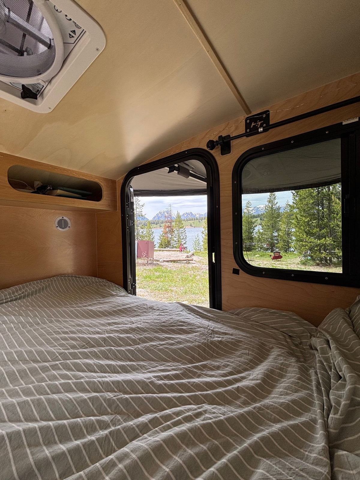  with mountain views and a cozy camper setup at a scenic campsite.|Cozy RV rental bedroom with a stunning lake — photo 5