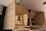An open, light wood RV rental overhead cabinet displaying organized beige dishes and dark cookware, ready for travel.