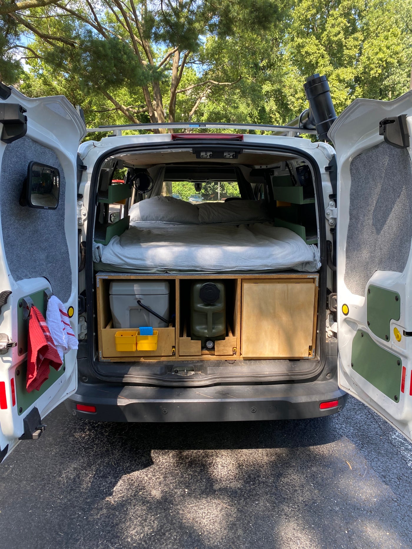 This cozy camper van conversion, perfect for an RV rental, shows its bed, toilet, and water setup, ready for adventure. — photo 3