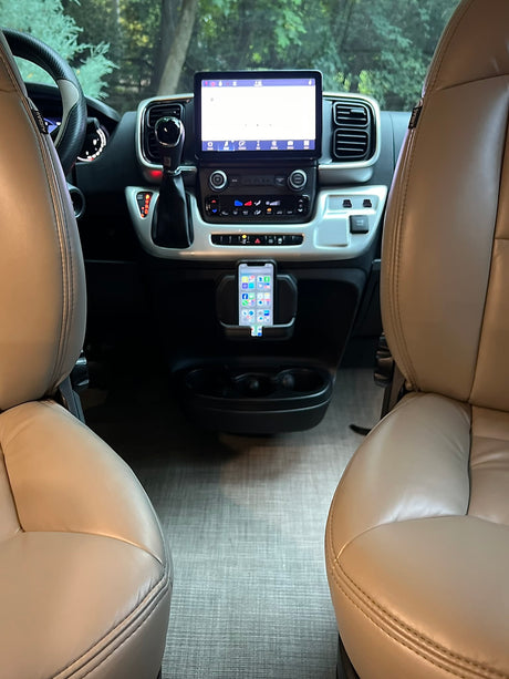 RV rental interior: beige seats frame a modern dashboard with a large infotainment screen and phone mount.