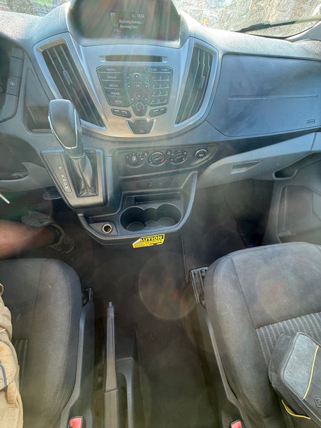 Interior view of an **rv rental** dashboard: gear shifter, radio, climate controls, and cupholders. Driver's leg and passenger seat visible.