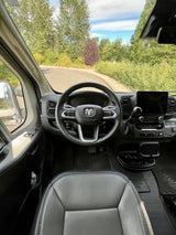Driver's view of a spacious RV rental interior: Ram steering wheel, dash, and winding road ahead.