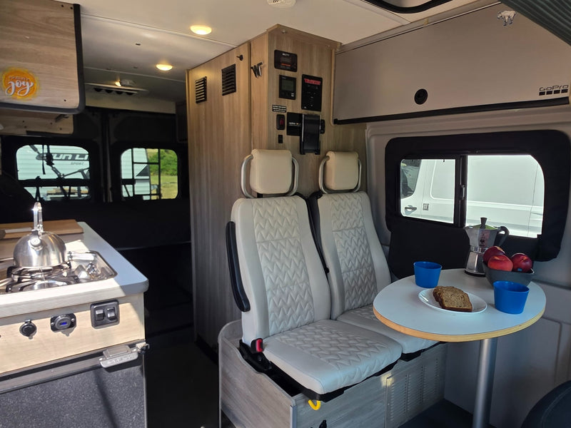  with mountains and the camper's interior lights glowing.|Bright RV rental interior featuring a kitchenette — photo 3