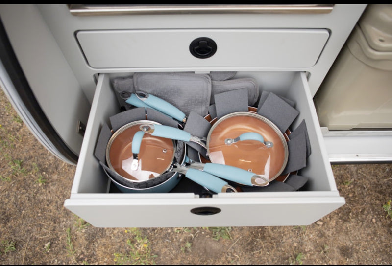 RV rental's kitchen drawer with organized blue-handled pots, pans, & gray protective pads for camping. — photo 8