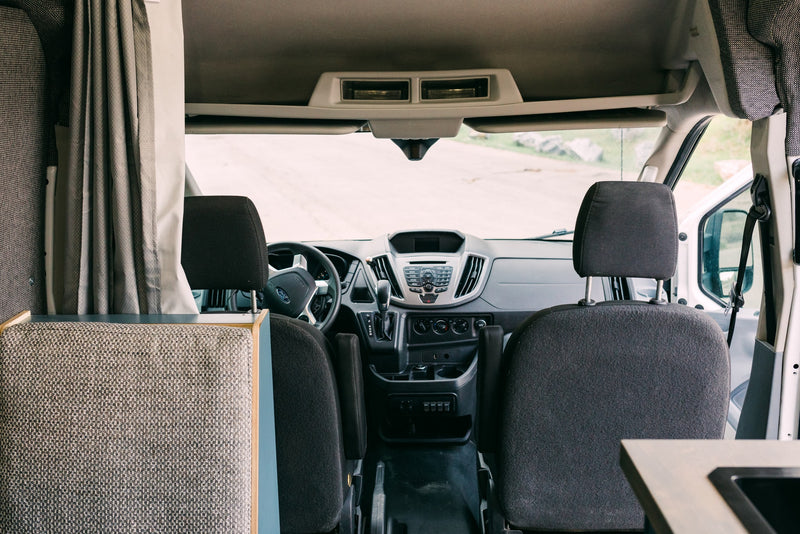RV rental interior: View from living area towards driver's cabin, showing front seats, dashboard, and road ahead. — photo 4