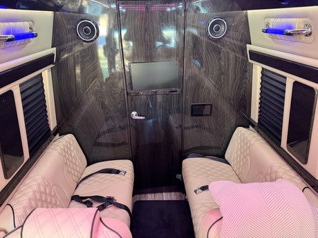 Explore this luxury RV rental: plush quilted seating, dark wood-grain interior, TV, premium audio, and blue ambient lighting.