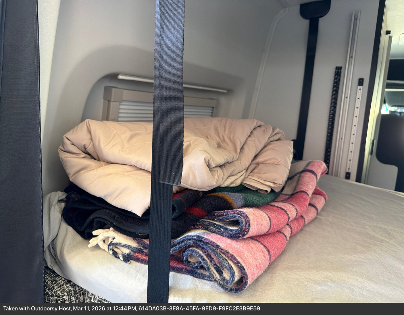 Stacked blankets & jacket on an RV rental bed, a cozy setup for your adventure.