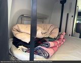 Stacked blankets & jacket on an RV rental bed, a cozy setup for your adventure.