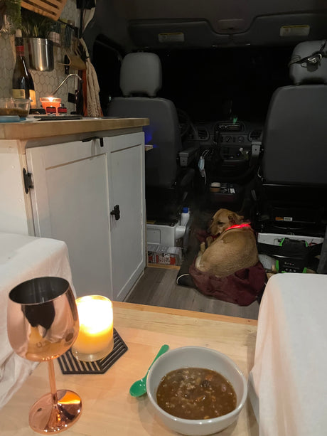 Cozy RV rental interior: dog snoozing, warm candle glow, and a hearty meal on a quiet night in.