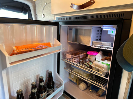 Inside an RV rental, this well-stocked refrigerator with drinks, eggs, and food is ready for your road trip.