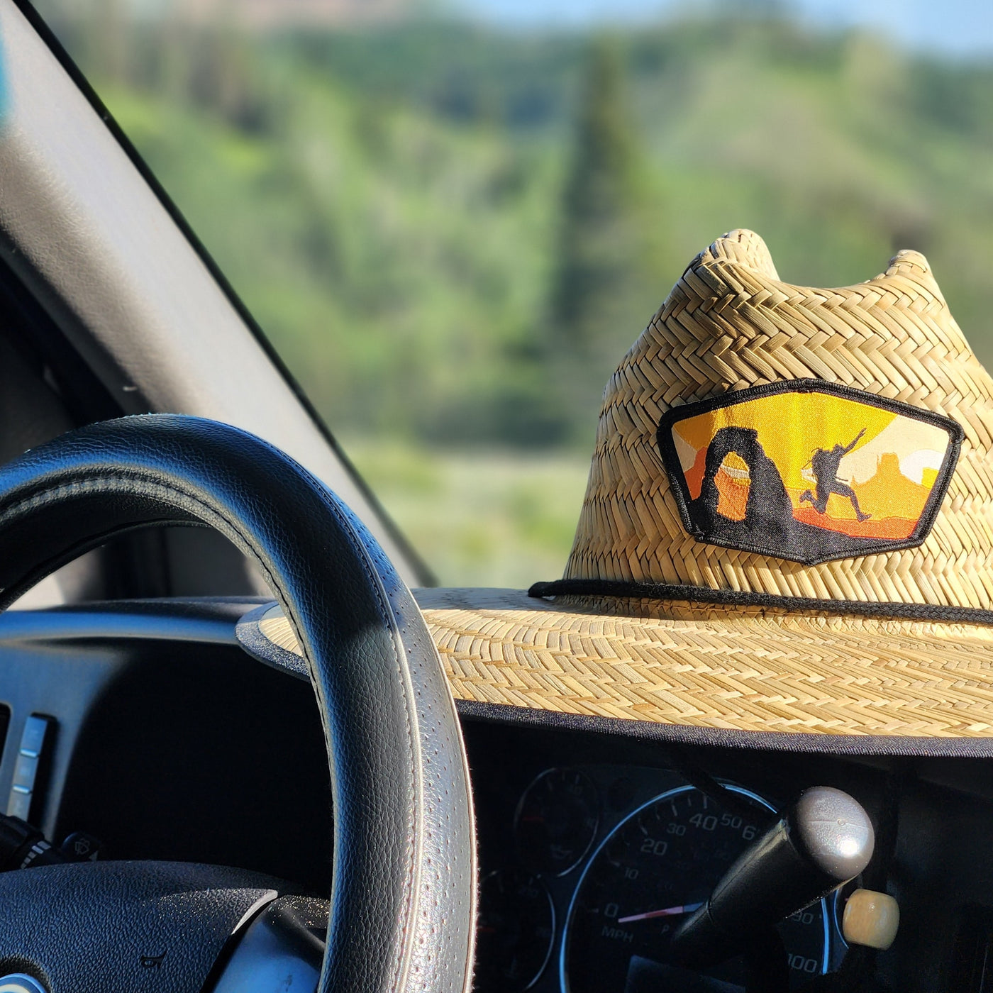 RV rental trip! Straw hat with desert arch patch on dashboard. Green landscape beyond windshield. — photo 2