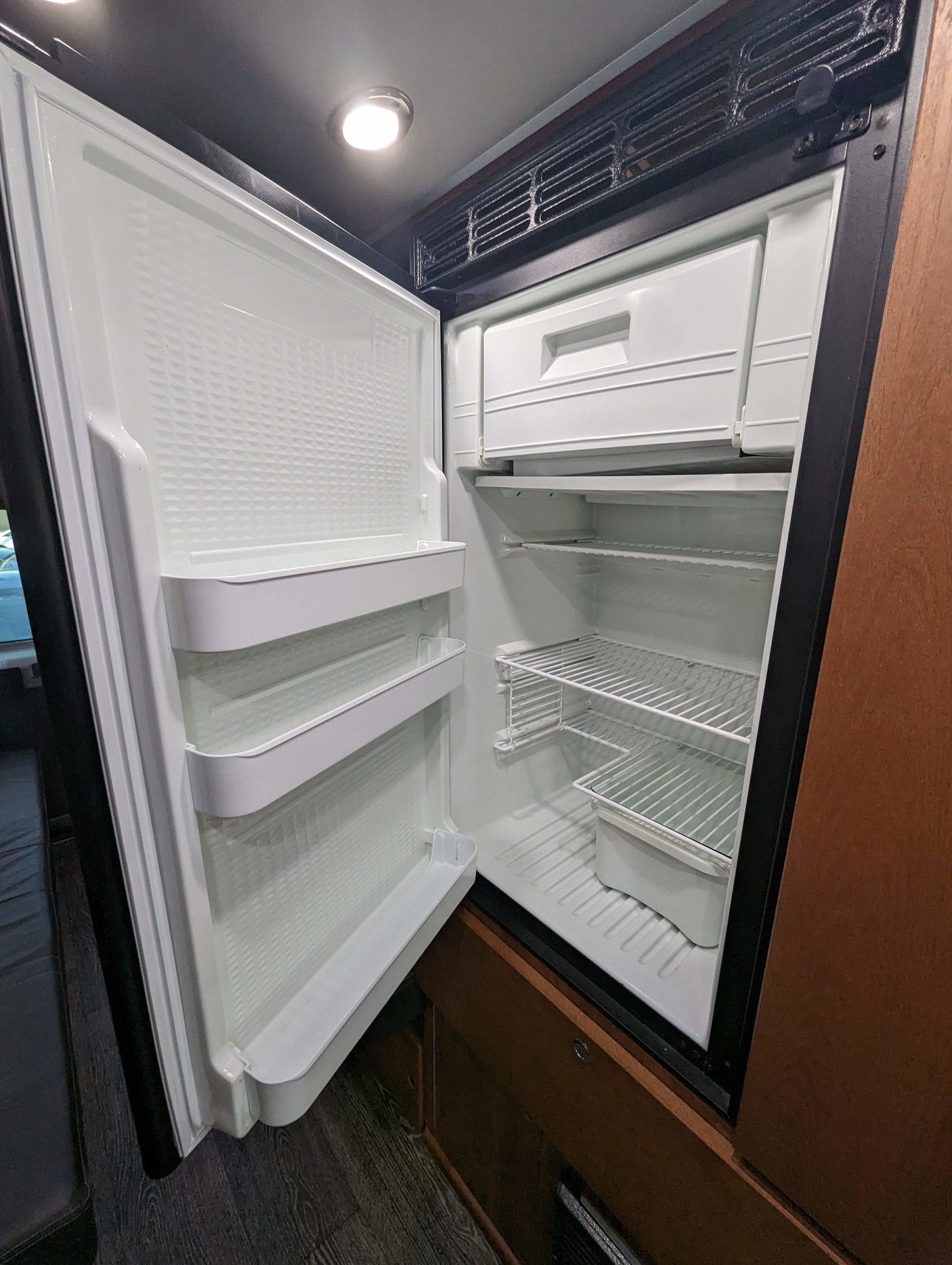 Inside a spacious, clean RV rental refrigerator with shelves & freezer. Enjoy travel comfort & fresh food on the go.