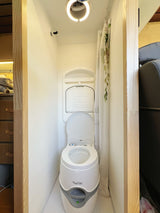 RV rental bathroom: a compact space with a portable Thetford Porta Potti toilet, shower, and ceiling light.