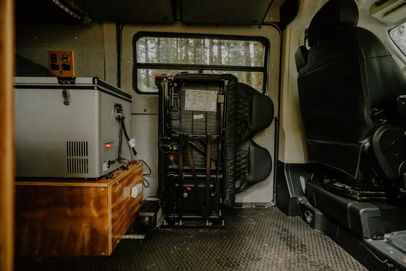 Experience comfort in this RV rental: portable fridge, folded rear seat, and essential power monitoring station. Van interior. — photo 6