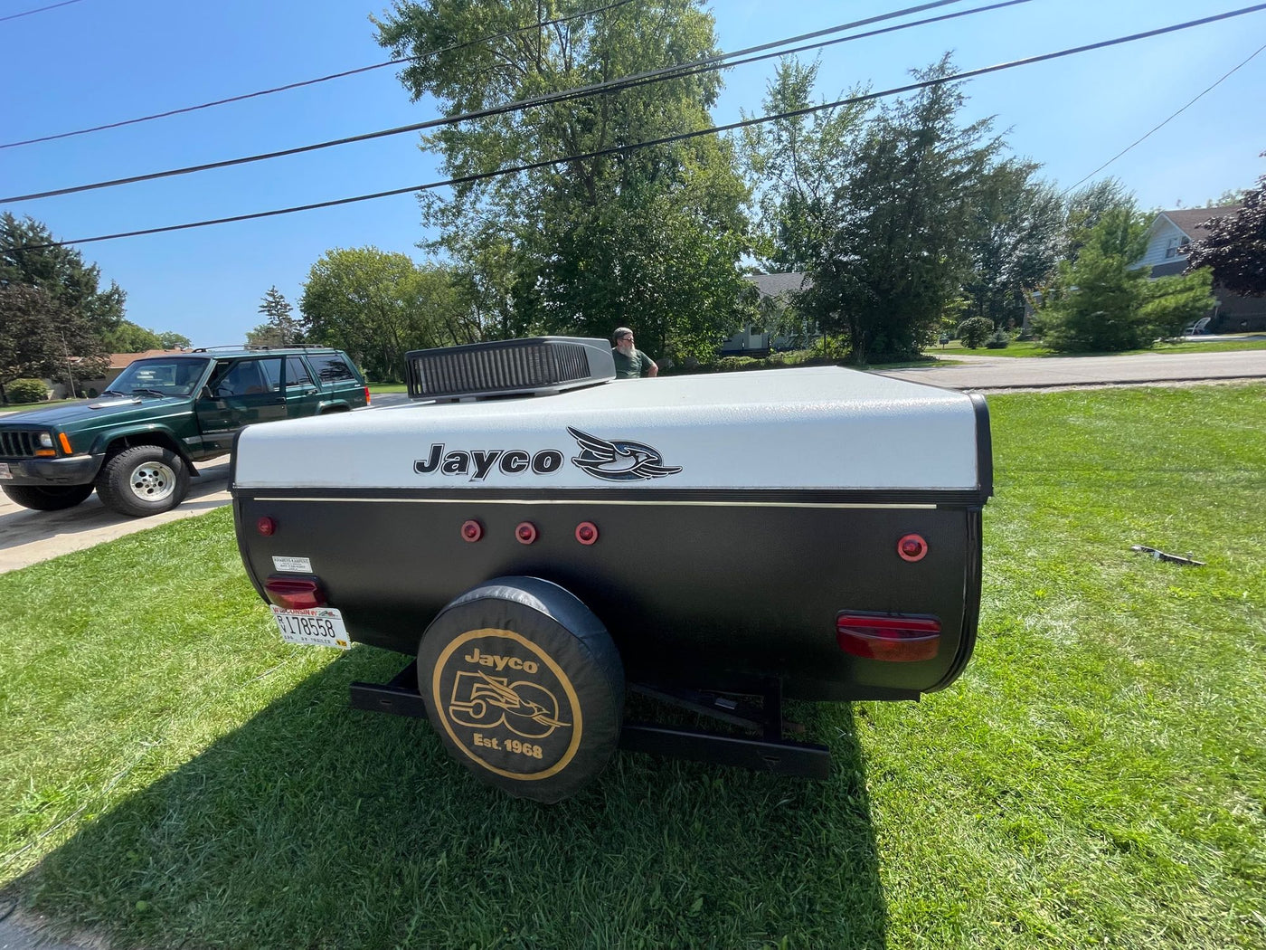 A black and white Jayco pop-up camper trailer and green Jeep are parked on a sunny lawn. Great for an RV rental adventure! — photo 10