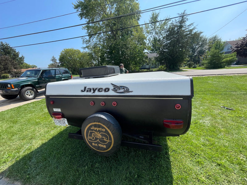 A black and white Jayco pop-up camper trailer and green Jeep are parked on a sunny lawn. Great for an RV rental adventure! — photo 10