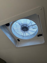Ceiling fan/vent with mesh screen and controls in an RV rental, providing ventilation for comfortable travel.