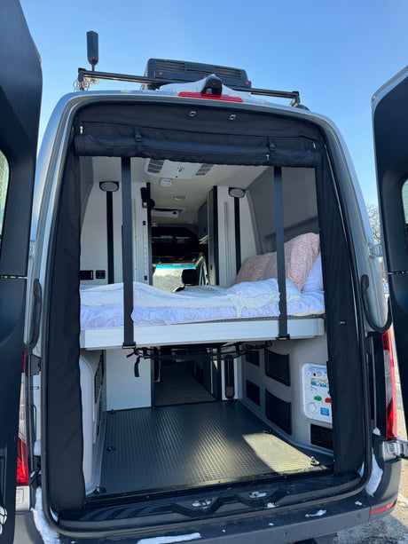 Open RV rental camper van showing an elevated bed, ample storage, and roof-mounted Starlink for connected travel.